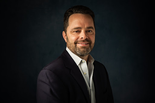 Headshot example photo of a man in a dark blazer against a dark studio background